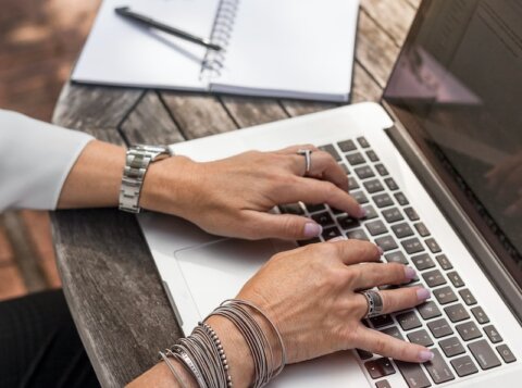 person typing on MacBook Pro on brown wooden table during daytime photo