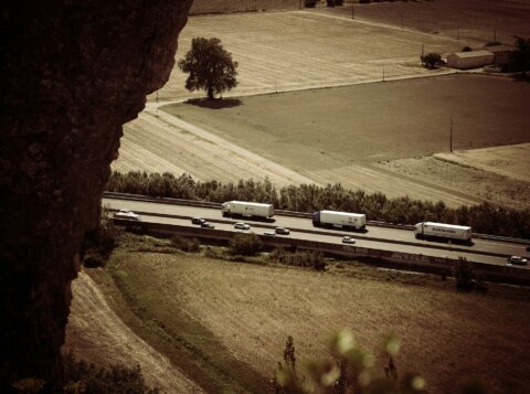 trail photography of running vehicles on street between grass field