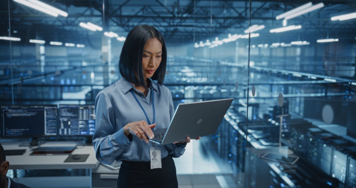 SmilingAsianFemaleDataCenterSpecialistAnalyzesServerPerformanceOn - AArete Employee using tech for strategy planning